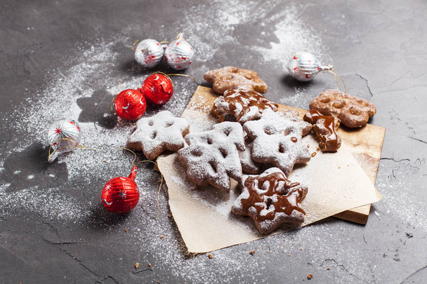 Christmas cookies with powdered sugar and candies on a wooden, cutting board on a gray background - Foto, Imagen