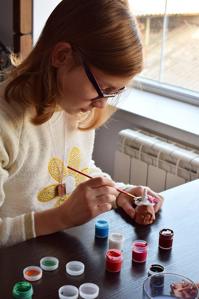 Dívka dělat do-it-yourself hračky, maluje hrnčířské hlíny hračka s kvaš. Uvnitř kreativní volného času pro děti. Podpůrné tvořivost, učí to, Diy projekt, ruční práce. Hlavní třída umění. - Fotografie, Obrázek
