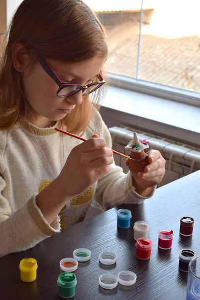 Tyttö tekee itsellesi leluja, maalaa keramiikkalelun guassilla. Sisätiloissa luova vapaa-aika lapsille. Luovuuden tukeminen, tekemällä oppiminen, DIY-projekti, käsityö. Taiteen mestariluokka
. - Valokuva, kuva