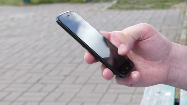 Férfi kézi megérinti a képernyőt egy mobil telefon-az utcán - Felvétel, videó