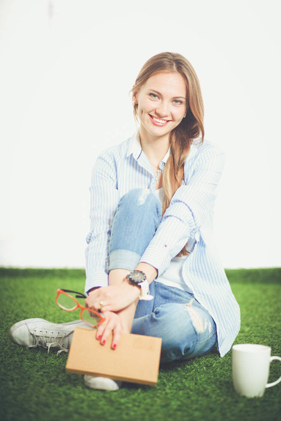 Young woman sitting with book on grass . Young woman - Foto, afbeelding