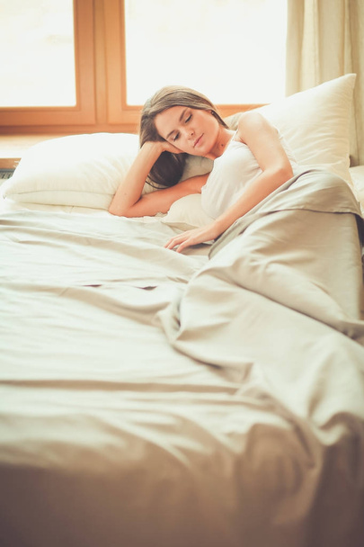 Beautiful brunette lying on bed at home - Фото, изображение
