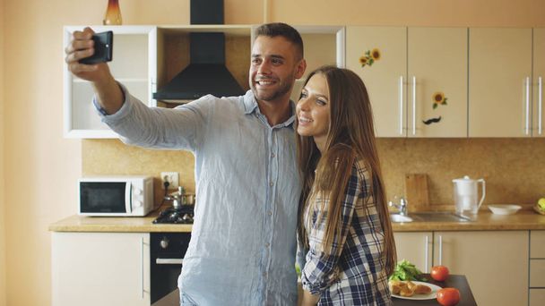 Молодая счастливая пара, имеющая онлайн видео чат на кухне дома
 - Фото, изображение