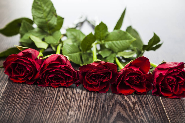 Red roses on a wooden background. - Zdjęcie, obraz
