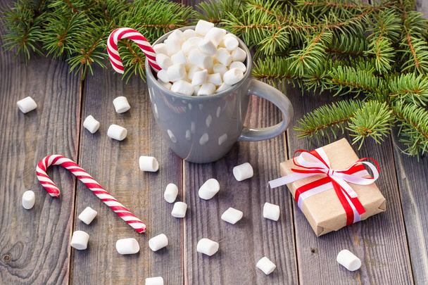 Hot coffee chocolate with marshmallow on rustic wooden table background, candy canes gift boxes fir tree - Fotó, kép