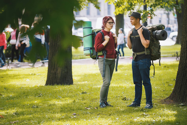 Mládež turisté s batohy mají konverzaci v parku v letní poledne - Fotografie, Obrázek