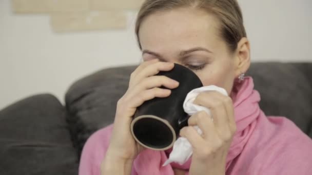 sick woman wipes his nose using a napkin and sheltered by a warm blanke - Video, Çekim