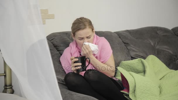 mulher doente limpa o nariz usando um guardanapo e protegido por um cobertor quente
 - Filmagem, Vídeo