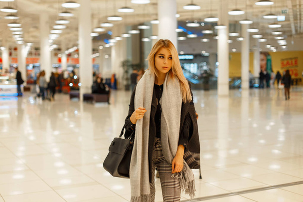 Bir eşarp ve alışveriş merkezinde siyah bir çanta ile trendy gri paltolu moda güzel kadın - Fotoğraf, Görsel