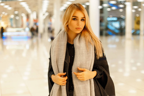 Hermosa mujer joven con un abrigo gris de moda con una bufanda elegante en el centro comercial
 - Foto, imagen
