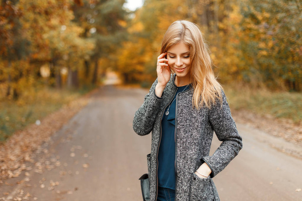 Jovem mulher bonita em um casaco de outono elegante andando no parque
  - Foto, Imagem