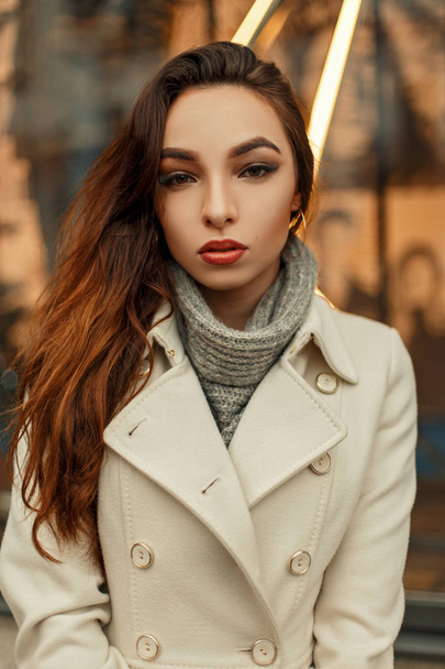 Beautiful stylish young brunette girl in trendy coat posing outdoors - Фото, зображення