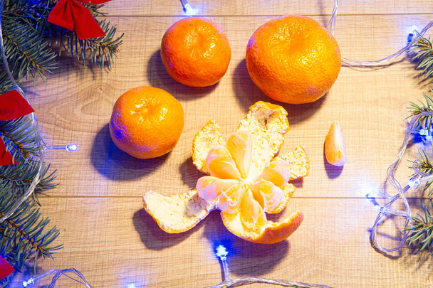 Ripe tangerines, New Year / Christmas tree with red bows and blue garland on the wooden background template - 写真・画像