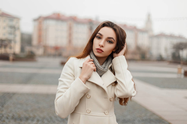 Beautiful young model girl in fashion coat with a sweater posing outside in the city on a winter day - Foto, Imagen
