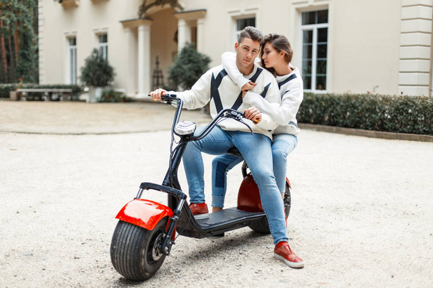 Piękna para zakochani w stylowej mody ubrania jazda rowerkiem elektronów w pobliżu hotelu - Zdjęcie, obraz