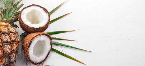 Coconut and pineapple on a wooden background. Tropical fruits and nuts. Top view. Free space for text. - Fotografie, Obrázek