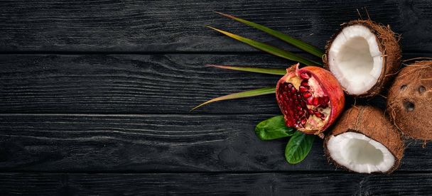 Pomegranate and coconut. Fresh fruits. On a wooden background. Top view. Free space for text. - Фото, изображение