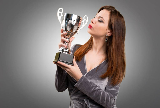 Beautiful young girl holding a trophy on textured background - Fotó, kép
