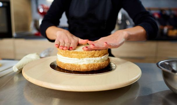 Hands of a confectioners woman with cake crusts on a table. - Foto, Imagen