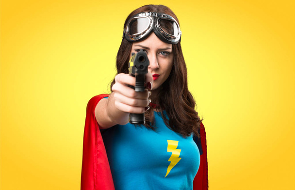 Симпатичная супергероиня с пистолетом на цветном фоне
 - Фото, изображение