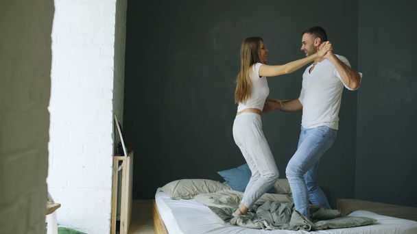 Young beautiful and loving couple dancing on bed in morning - Foto, afbeelding