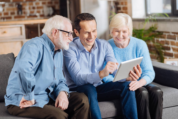 Cheerful son teaching his senior parents how to use tablet - Foto, afbeelding
