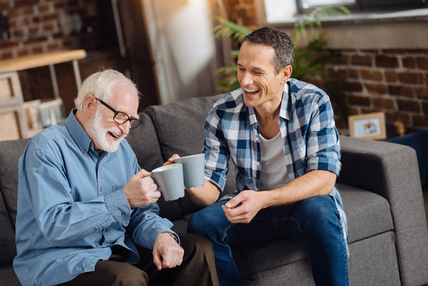 Pleasant young man drinking tea with his elderly father - Photo, Image
