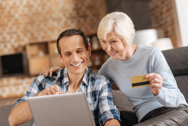Elderly woman and her son doing online shopping together - Foto, Bild