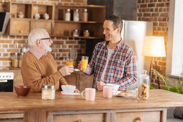 Charming man and his elderly father drinking juice - Foto, imagen