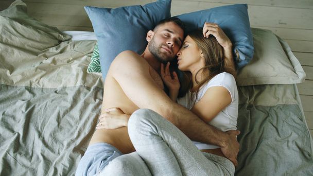 Young beautiful and loving couple kissing on bed in the morning - Fotoğraf, Görsel