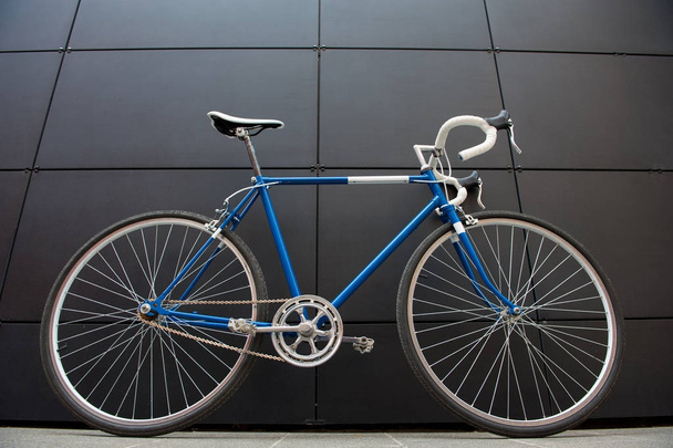 Vintage blue city bicycle on a black wall - 写真・画像
