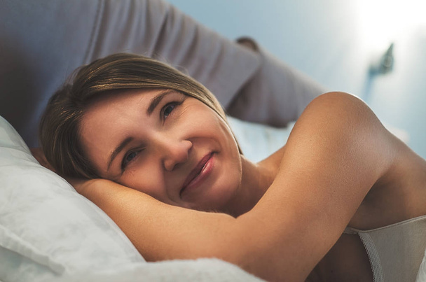 Красивая женщина с длинными светлыми волосами в постели после пробуждения. Утренний сон и отдых дома
 - Фото, изображение