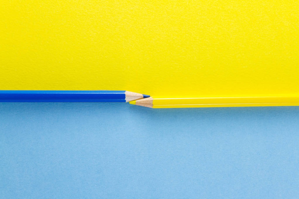 Renkli kalemler, sarı ve mavi renkli kağıtlara horizonta düzenlenmiş - Fotoğraf, Görsel