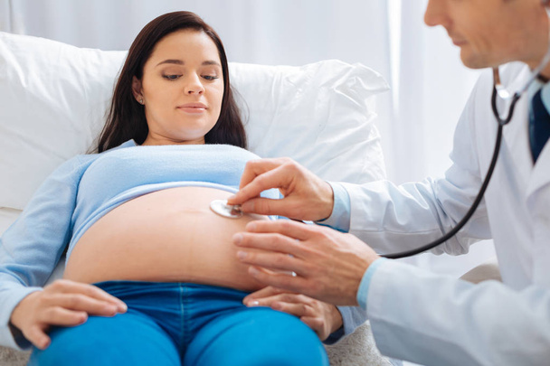 Rätselhafte junge Frau blickt auf ihren Babybauch - Foto, Bild