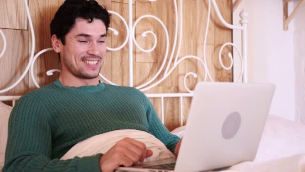 Vidéo en ligne Chat sur ordinateur portable par homme allongé au lit, relaxant
 - Séquence, vidéo