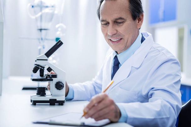 Cheerful positive scientist writing an analysis - Foto, Imagem