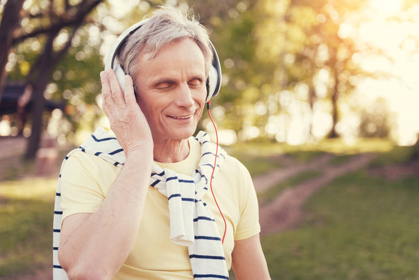 Delighted aged man wearing headphones - Foto, afbeelding
