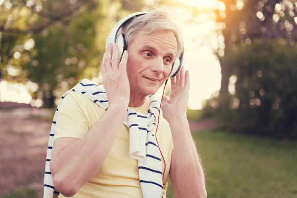 Positive delighted man holding his headphones - Fotó, kép
