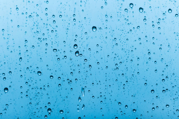 Grandes gotas de lluvia sobre un fondo de vidrio azul
. - Foto, imagen