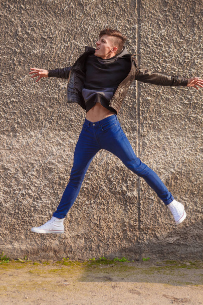 jumping stylish young brunet in leather jacket - Фото, зображення