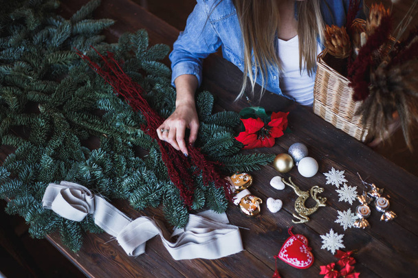 Decorator holds christmas toys in her hands, start to prepare christmas wreath - Fotó, kép
