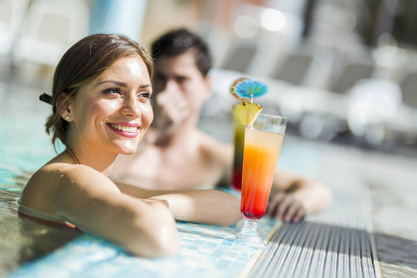 Couple drinking a cocktails by the swimming pool - Photo, image