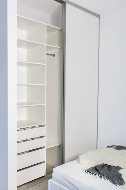 Modern home interior.Built-in wardrobe with sliding doors in the light interior of the bedroom. Small room. One of the doors of the built-in wardrobe is open. European furniture, design, technologies. - Photo, Image