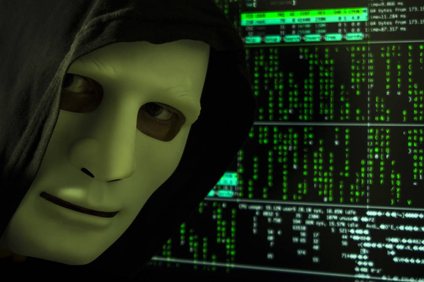 De hacker in de kap en het masker op de achtergrond van de digitale code. - Foto, afbeelding
