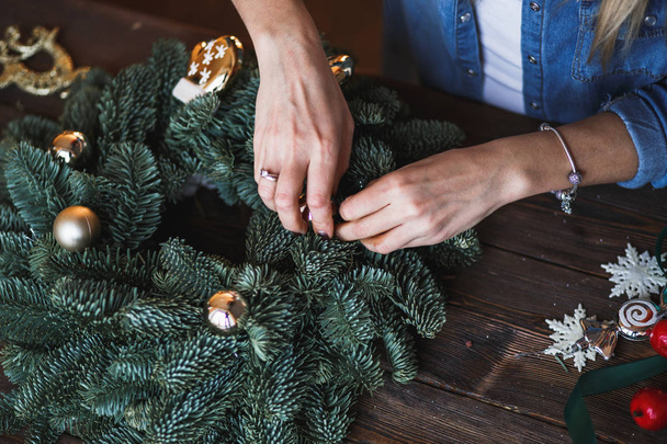 Decorator prepares christmas wreath with fir branches and toys - Fotoğraf, Görsel