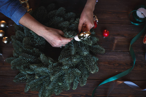 Decorator prepares christmas wreath with fir branches and toys - Фото, зображення
