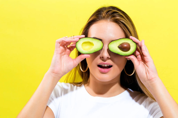 Happy young woman holding avocado halves - Фото, изображение