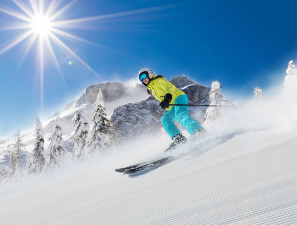 Young woman skier running down the slope in Alpine mountains.  - 写真・画像