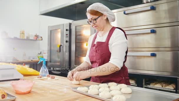 Доросла добра усміхнена жінка випікає і формує м'ясні пироги в пекарні
 - Кадри, відео