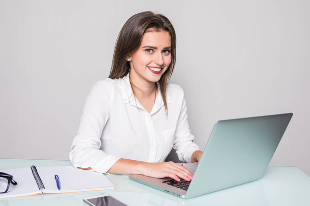 Elegant and cheerful businesswoman. Cheerful young beautiful woman looking at camera with smile while sitting at her working place - Foto, imagen